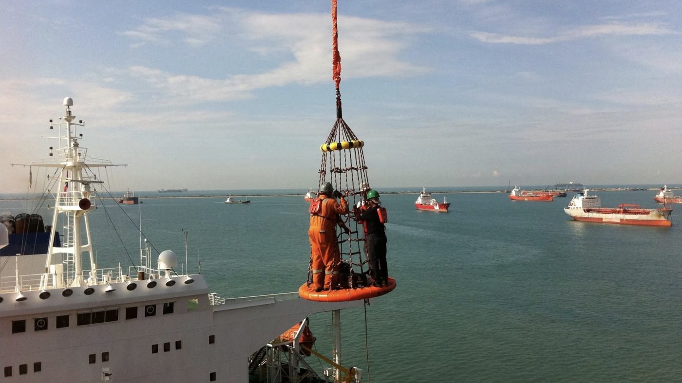 Offshore personnel transfer by crane basket, with crew in survival suits and life jackets